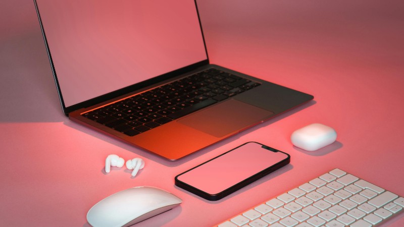 Contemporary desk setup featuring a laptop, smartphone, wireless mouse, keyboard, and earbuds in a stylish pink hue., tags: ruhe der digitalen - pexel