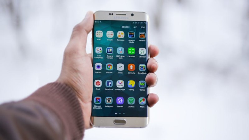 Close-up of a hand holding a Samsung smartphone displaying various app icons, emphasizing technology and connectivity. - Close-up of a hand holding a Samsung smartphone displaying various app icons, emphasizing technology and connectivity., tags: mehr - pexel